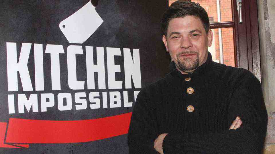 Star chef Tim Mälzer in front of a poster by "Kitchen Impossible"