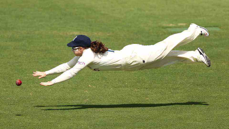 A woman dives for a ball on a field