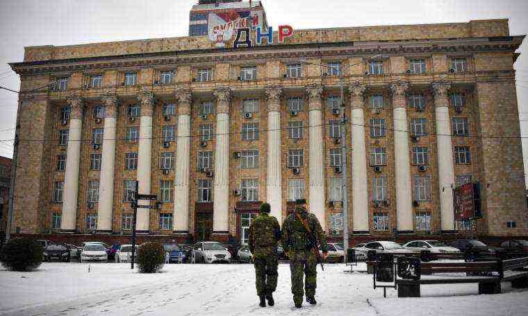 Two pro-Russian separatist fighters walk near an official building in Donestsk, eastern Ukraine, on January 18, 2022 (AFP/Alexander NEMENOV)