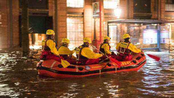 Rescuers from the DLRG drive along the flooded Hamburg fish market in a rubber dinghy: but they didn't have to save anyone.  (Source: dpa/Daniel Bockwoldt)