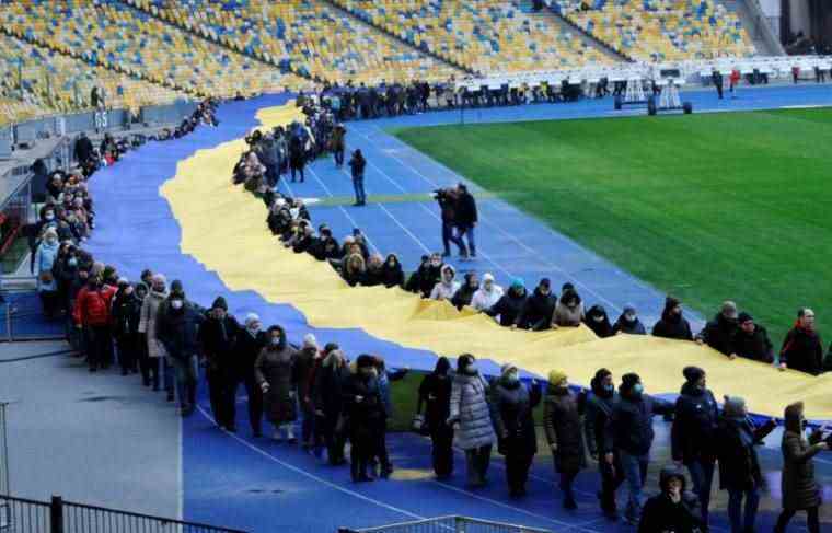 A giant Ukrainian flag unfurled in Kyiv to celebrate Unity Day, February 16, 2022 (AFP/SERGEI CHUZAVKOV)