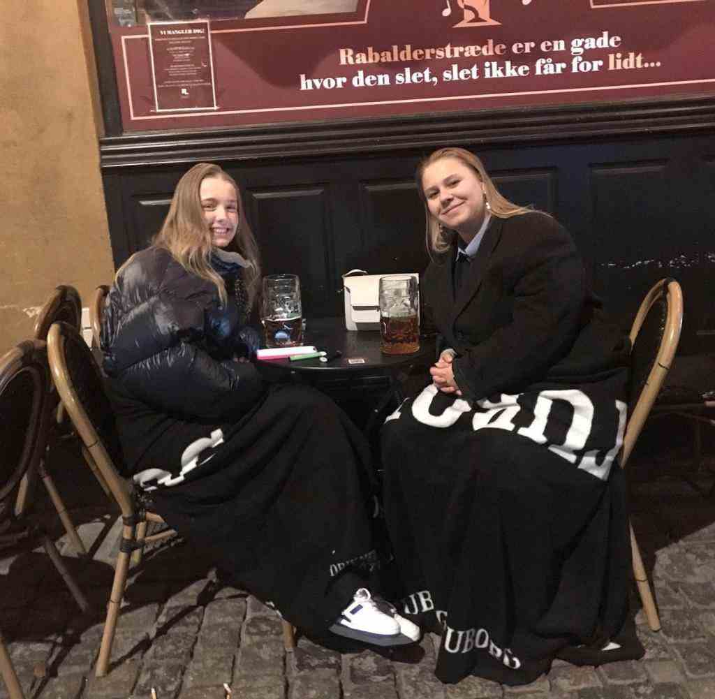 Pure hygge: Two young women make themselves comfortable in front of a bar in Copenhagen