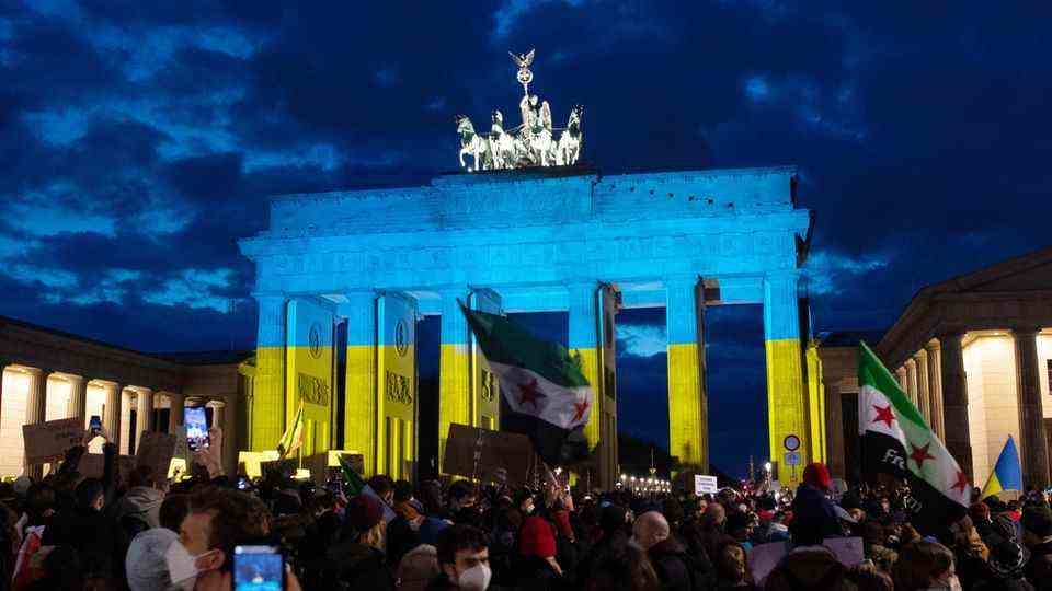 The Brandenburg Gate is illuminated in the colors of Ukraine in the evening during a solidarity demonstration for Ukraine