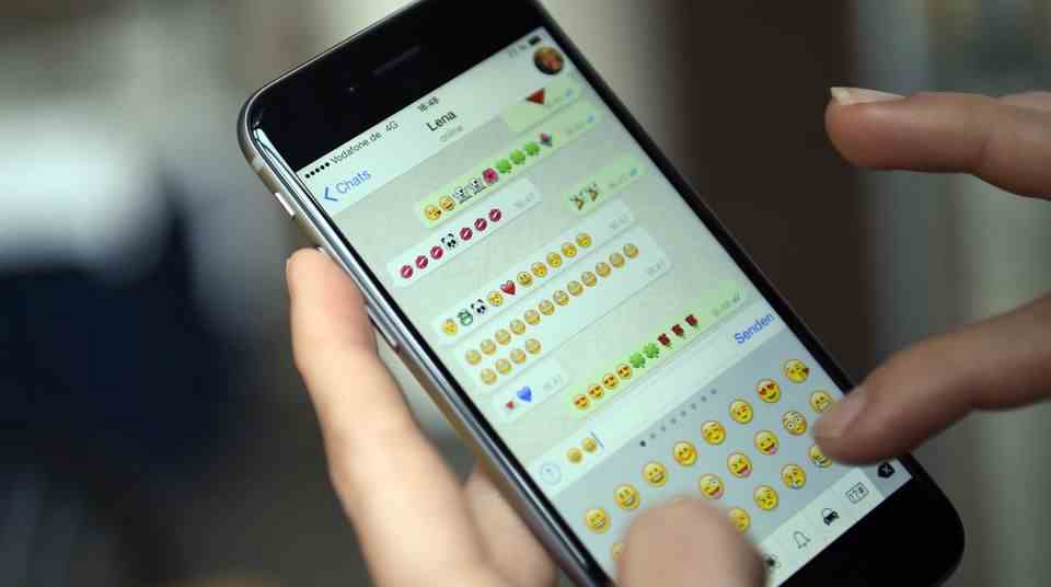 A smartphone shows a WhatsApp chat in which only emoticons are sent back and forth.