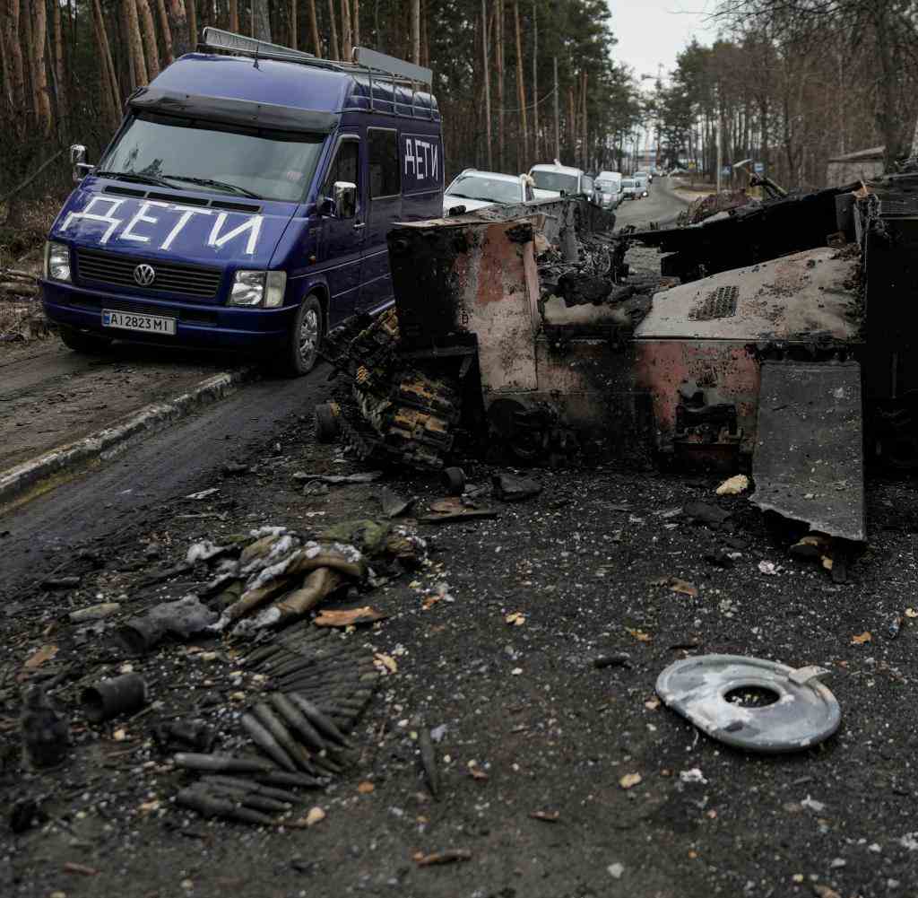 Ein Lieferwagen mit der Aufschrift "Kinder" vor einem zerstörten russischen Panzer