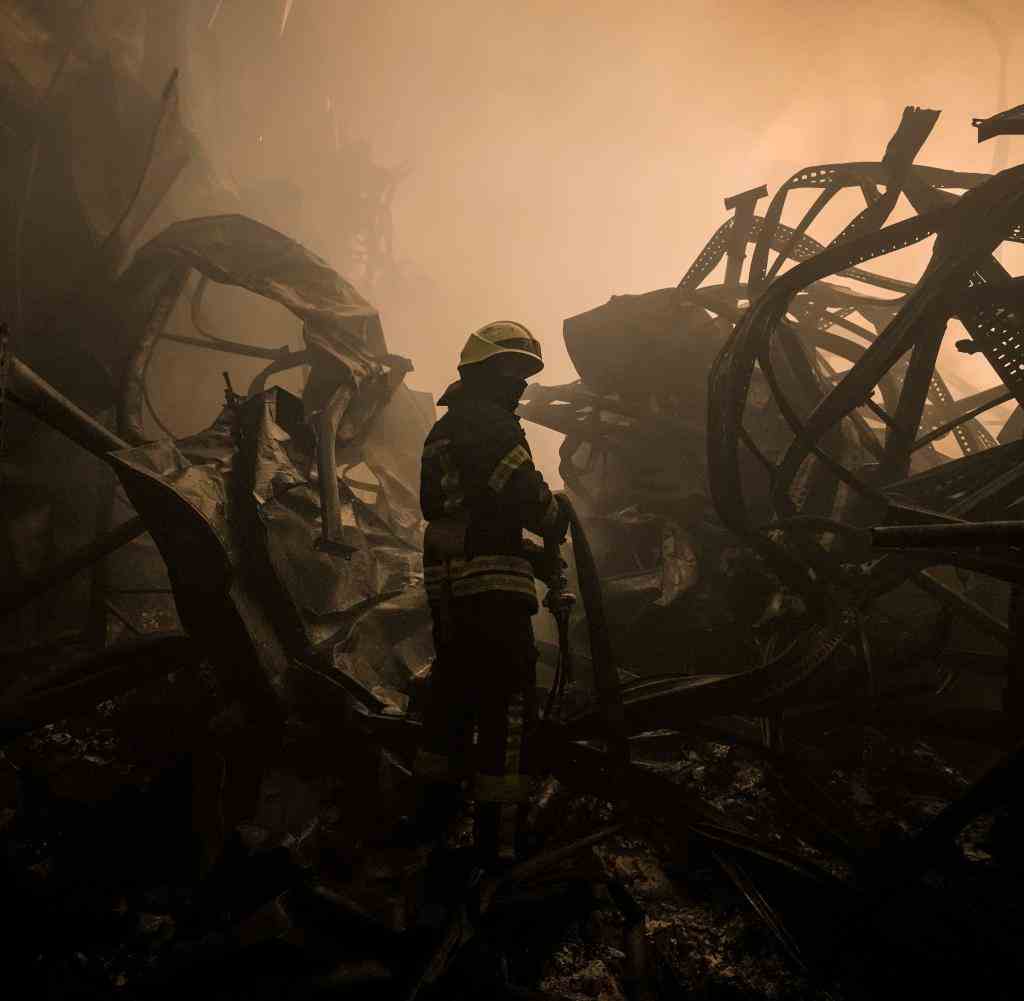 A Ukrainian firefighter at a food warehouse destroyed by an airstrike in the early hours of the morning on the outskirts of Kyiv