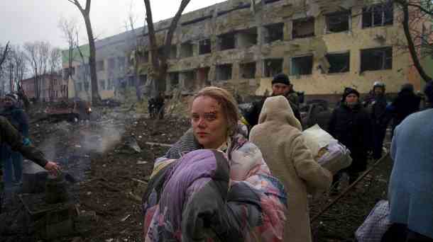 Eine Frau steht vor einem durch Beschuss beschädigten Entbindungskrankenhaus in Mariupol: In der Stadt sind bereits mehr als 2.100 Zivilisten ums Leben gekommen. (Quelle: dpa/Mstyslav Chernov)
