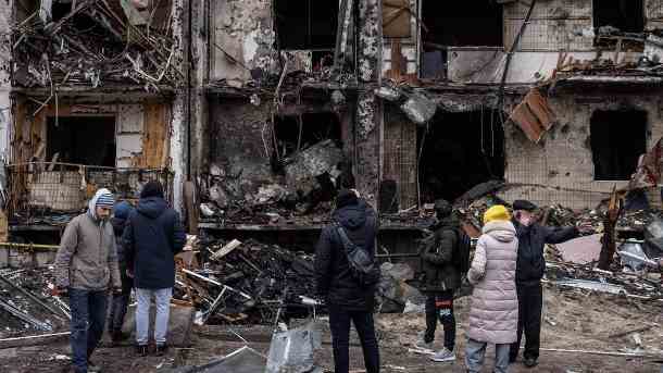 Menschen stehen vor einem zerstörten Haus in Kiew: Dutzende Menschen mussten in der Stadt in einem Massengrab beigesetzt werden. (Quelle: Getty Images/Chris McGrath)