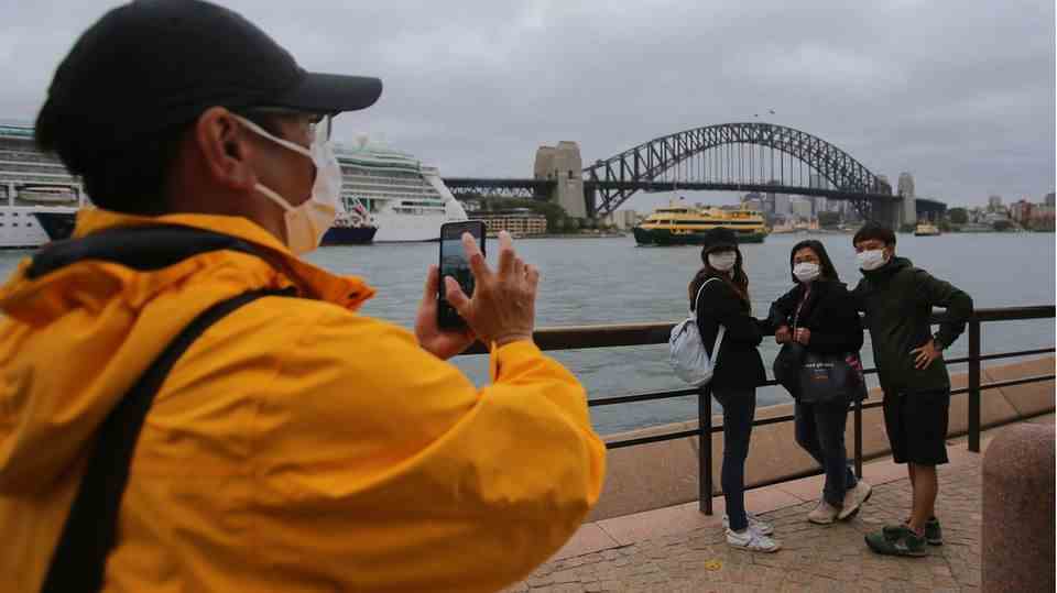 Tourists pose for photos in front of the Harbor Bridge in Australia