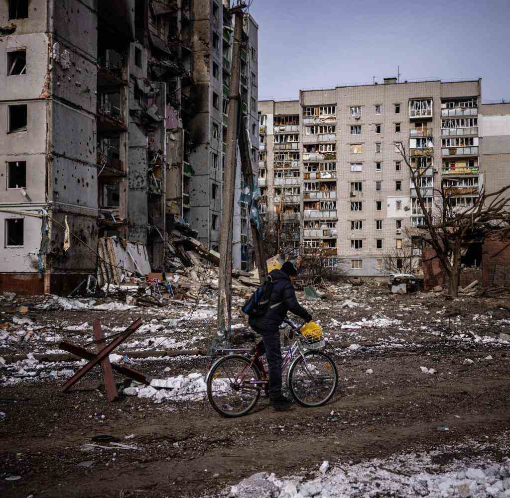 A man rides his bicycle in front of residential buildings damaged in yesterday's shelling in the city of Chernihiv on March 4, 2022. - Fourty-seven people died on March 3 when Russian forces hit residential areas, including schools and a high-rise apartment building, in the northern Ukrainian city of Chernihiv, officials said. (Photo by Dimitar DILKOFF / AFP)