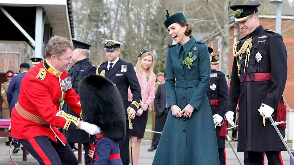 March 18, 2022 As the child's head disappears under the hat, Kate bursts out laughing Royal fans love this laugh!  Duchess Kate and Prince William attended the annual St. Patrick's Day parade in Aldershot on Thursday.  They were received by Lieutenant Colonel Rob Money and his 20-month-old daughter Gaia, among others.  First, Kate was given two bouquets of flowers – but the little girl also wanted to have them.  Of course, the mother of three left the sweet little ones with the flowers.  Later, Gaia requested to wear her father's bearskin hat.  The sight delighted the royal guests so much that they burst out laughing.