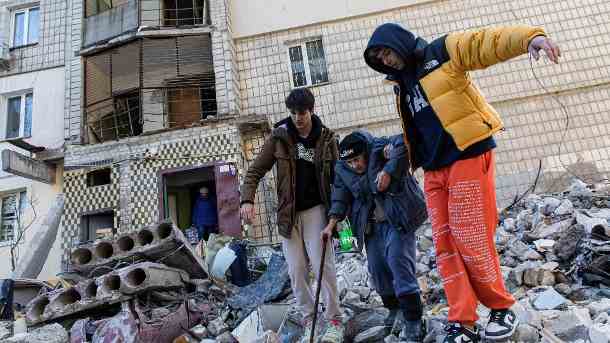 Kiew: Zwei Männer helfen einer alten Frau, über die Trümmer eines zerstörten Wohngebäudes zu gehen. (Quelle: dpa/Alex Chan Tsz Yuk/SOPA Images via ZUMA Press Wire)