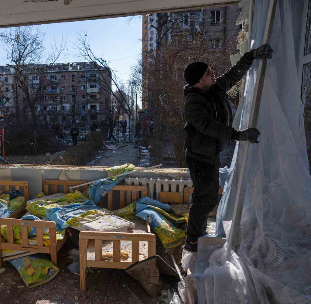 Kyiv: A man removes a destroyed curtain at a school that was damaged next to other apartment buildings.