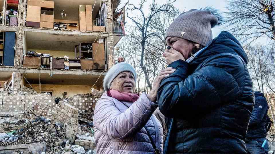 Two women mourn in front of a bombed house in Kyiv