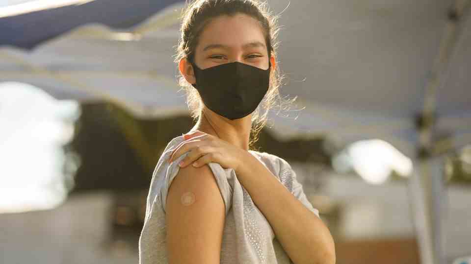 A young woman shows her vaccinated arm