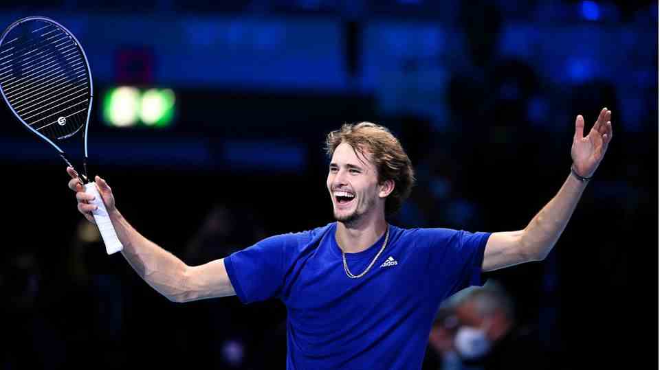 Laughing Alexander Zverev with his hands up and a tennis racket