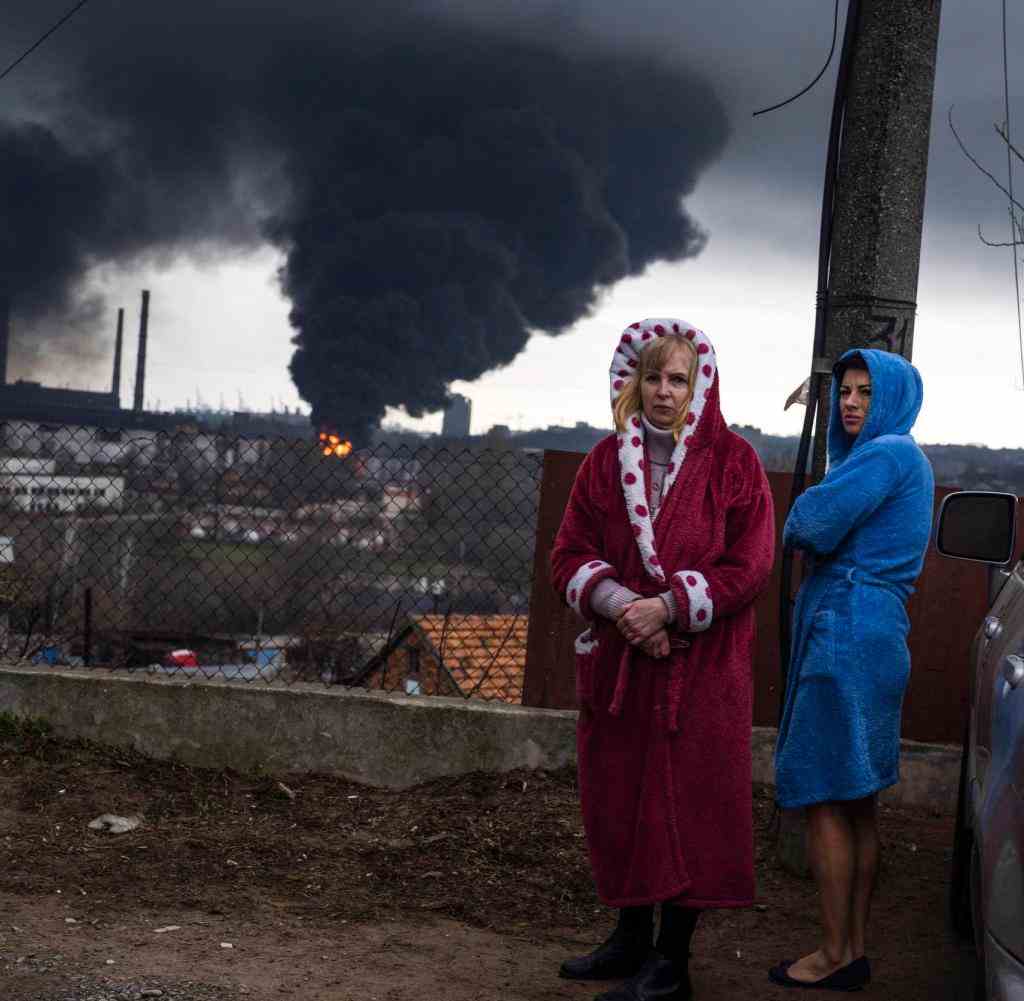 Women stay next to a car as smoke rises in the air in the background after shelling in Odesa, Ukraine, Sunday, April 3, 2022. (AP Photo/Petros Giannakouris)