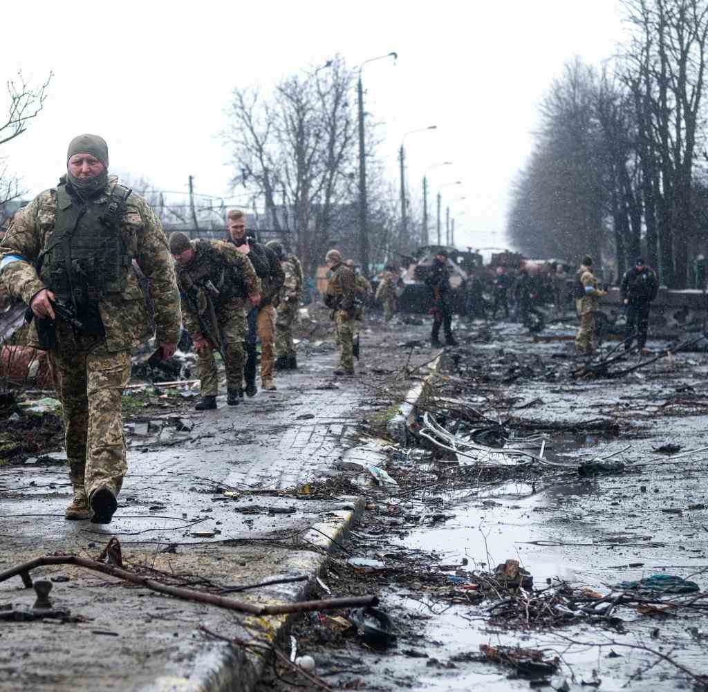 Ukrainische Soldaten inspizieren die Trümmer einer zerstörten russischen Panzerkolonne in Butscha