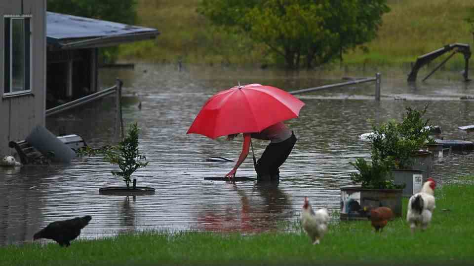 Woman stands in her flooded garden in Australia