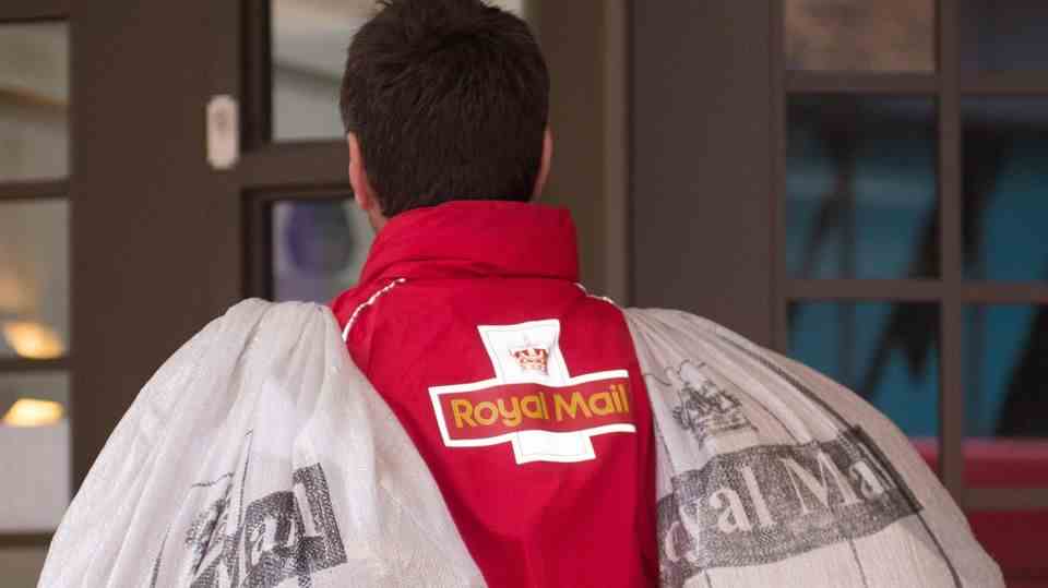 A postman carries two sacks with the inscription "Royal Mail"