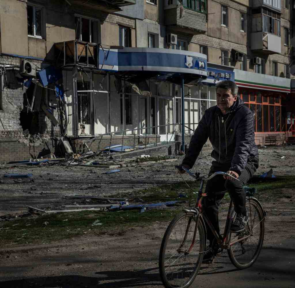 A man rides a bicycle past an apartment building damaged by a previous Russian attack, IN Sieverodonetsk