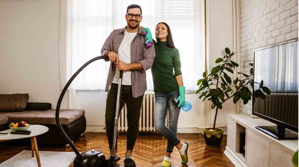 A young couple cleans the living room together