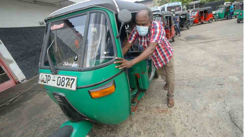 A man pushes his tuk-tuk to a gas station in Sri Lanka.