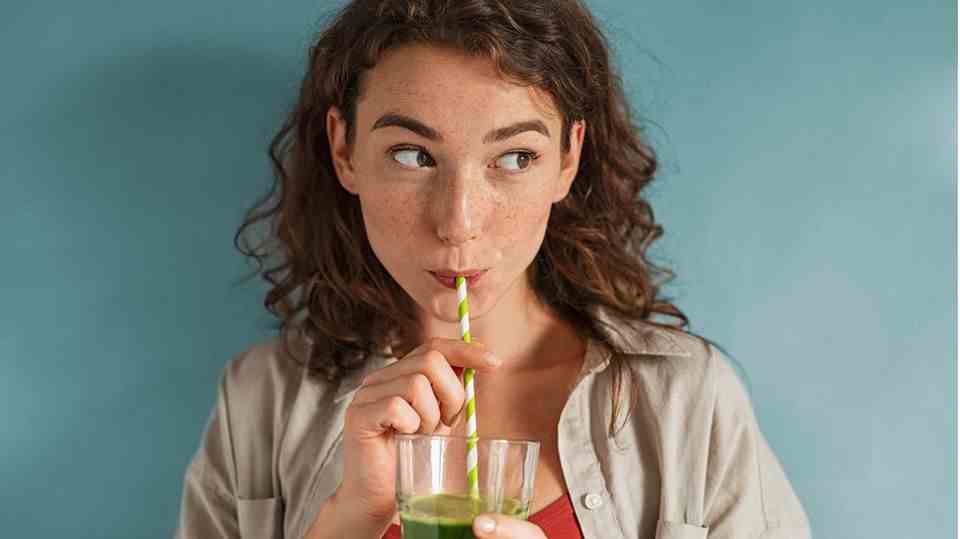Girl drinks green juice from a straw