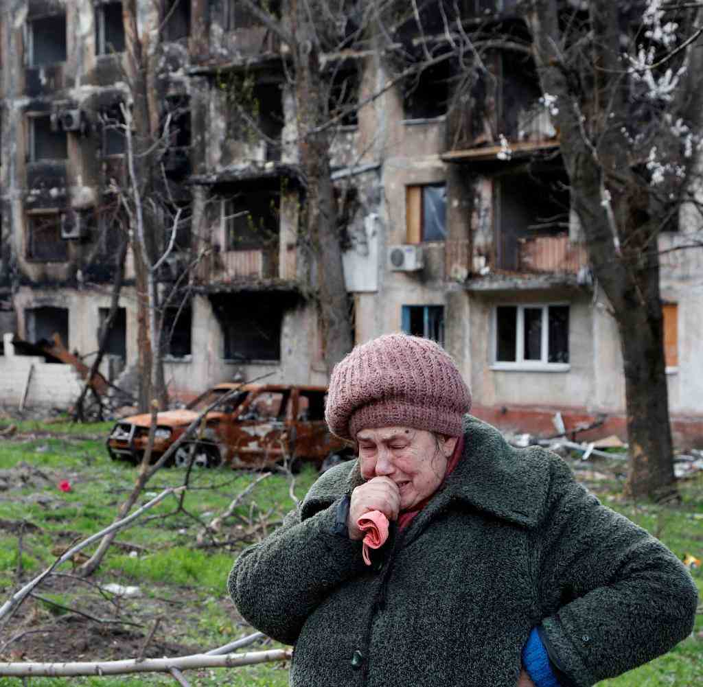 Eine Frau vor einem völlig zerstörten Gebäude in Mariupol