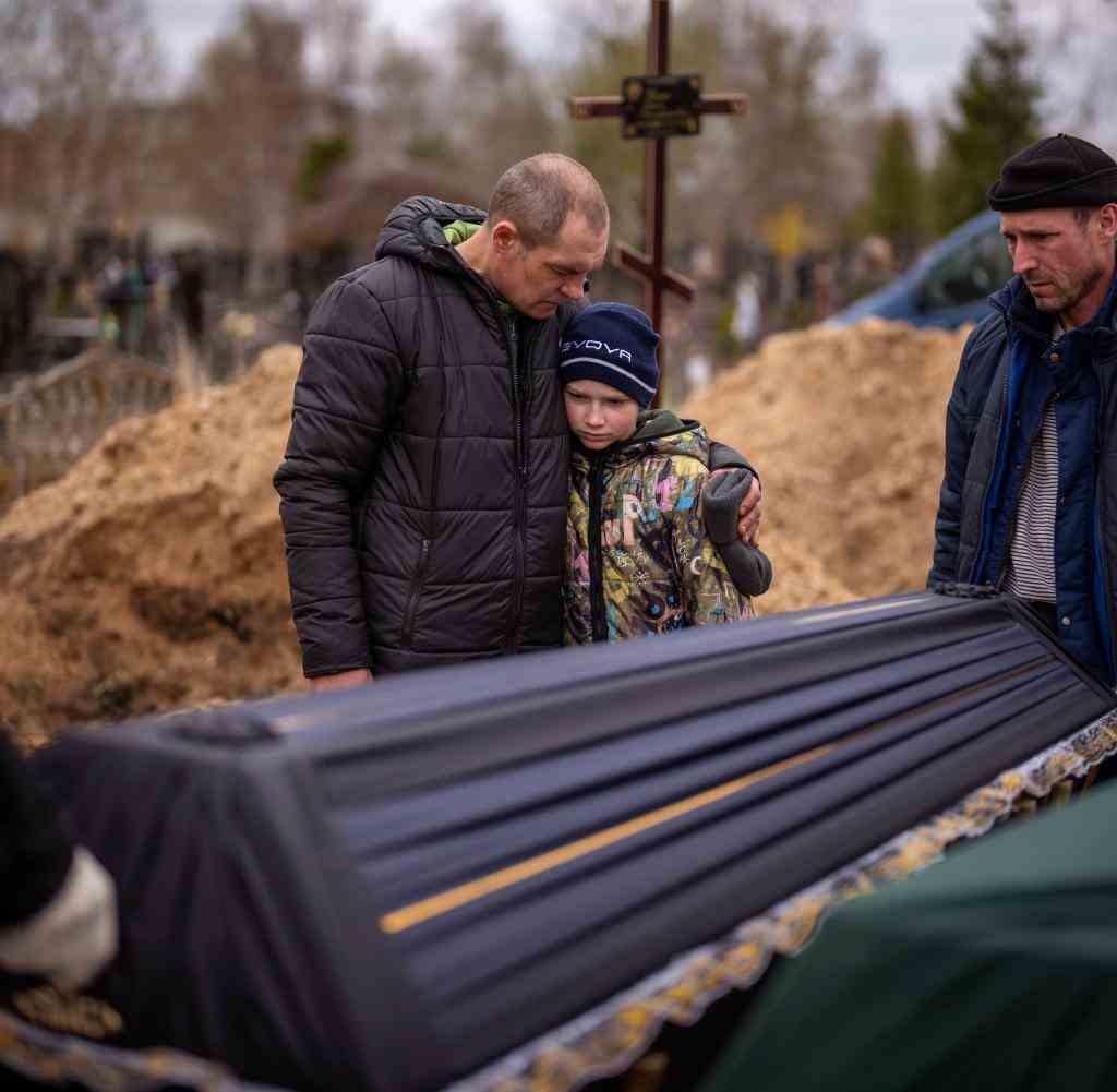 Ein Vater und sein Sohn bei der Beerdigung der Mutter, die von russischen Soldaten in Butscha getötet wurde