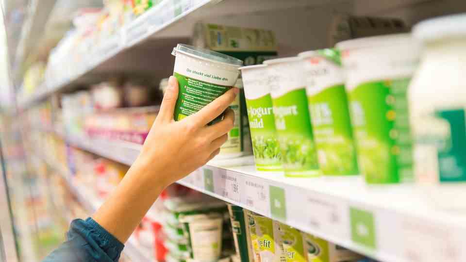 Woman gets yoghurt cups from the supermarket shelf