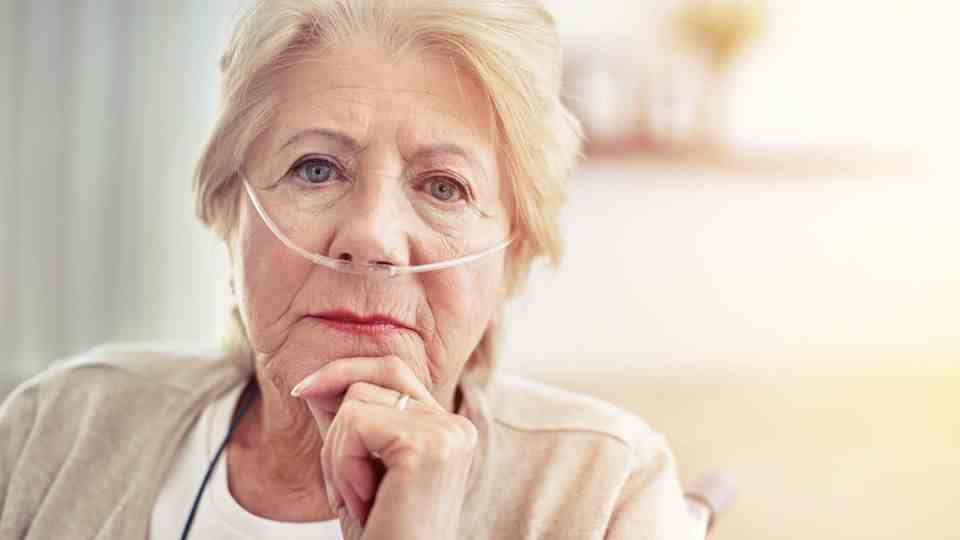 A woman in her 80s wears tubes in her nose through an oxygen machine