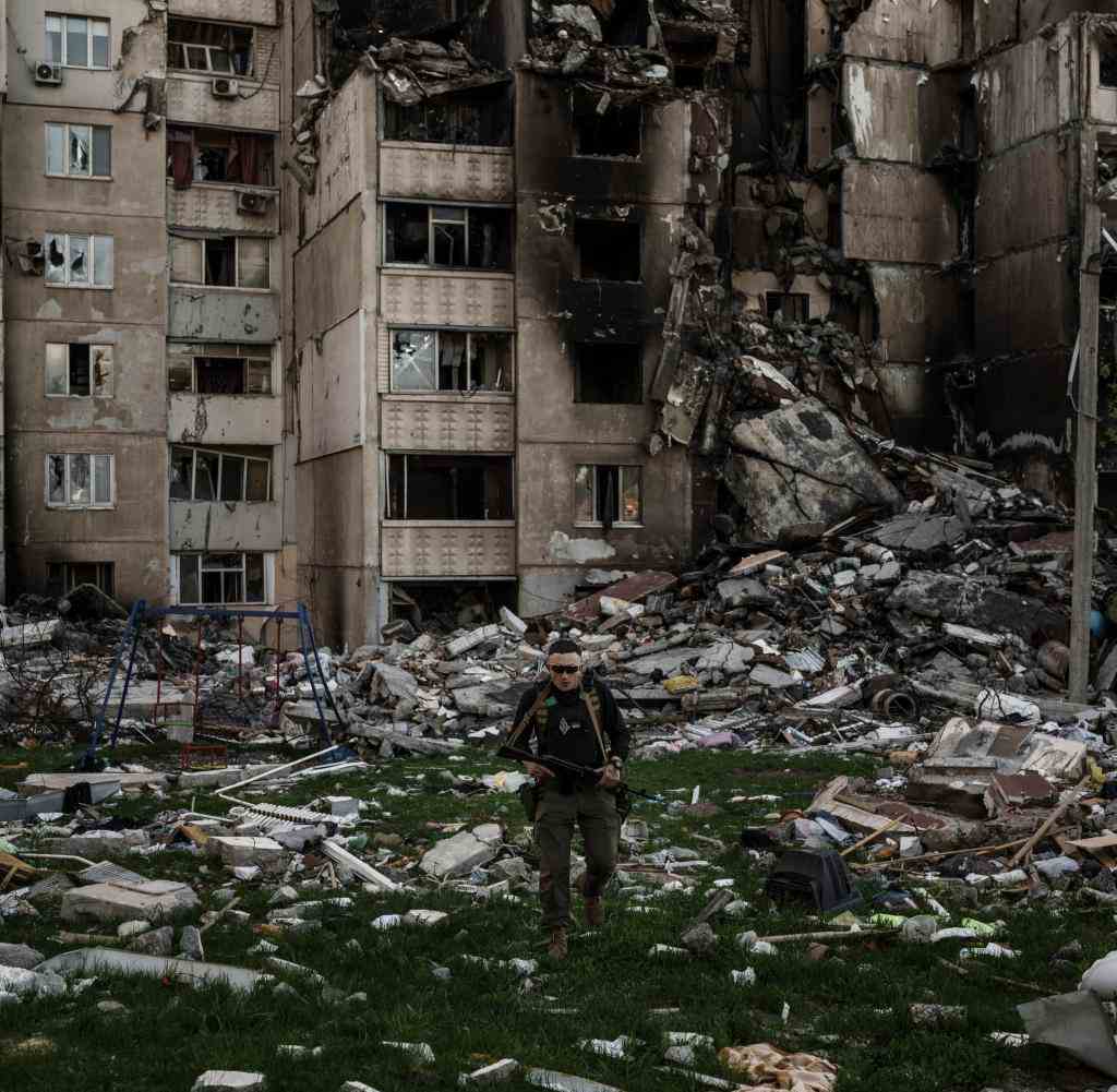 Ein ukrainischer Soldat geht inmitten der Trümmer eines Gebäudes, das durch mehrfachen russischen Beschuss in der Nähe einer Frontlinie schwer beschädigt wurde