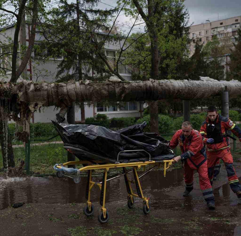 Rettungskräfte mit der Leiche eines Mannes, der während eines russischen Bombardements in Charkiw getötet wurde