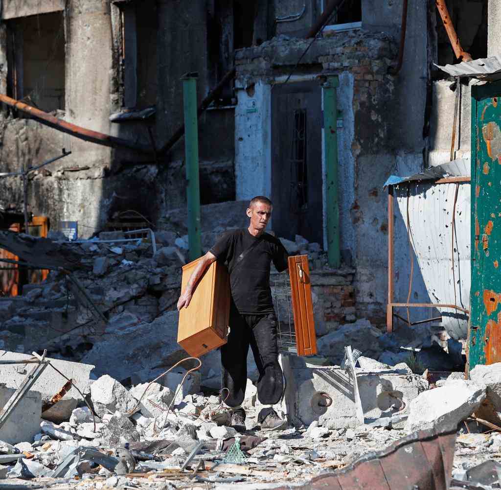 Ein Mann bringt brauchbare Möbel aus einem zerstörten Haus in Mariupol