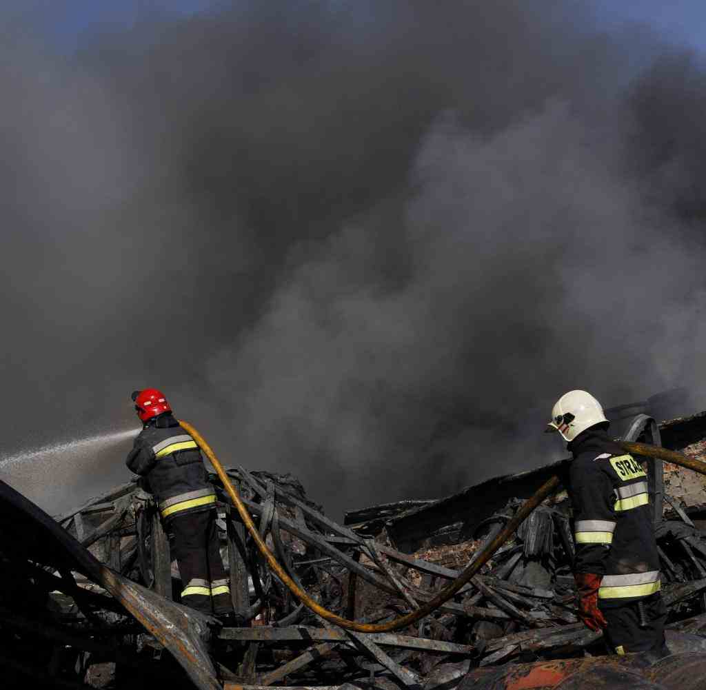 Firefighters try to put out a fire at a factory in Kharkiv that was hit by a Russian missile