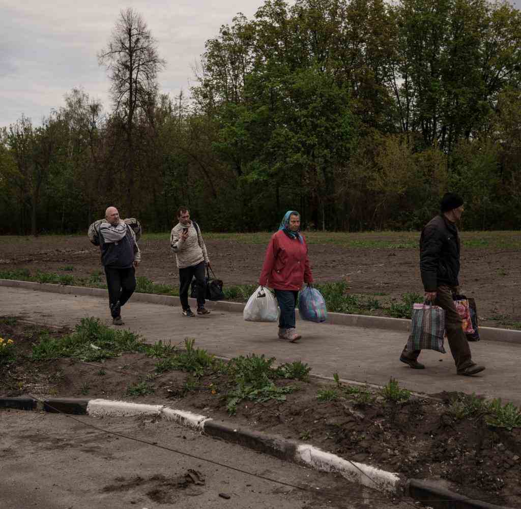 People who fled the village of Ruska Lozova go with their luggage to a checkpoint in Kharkiv