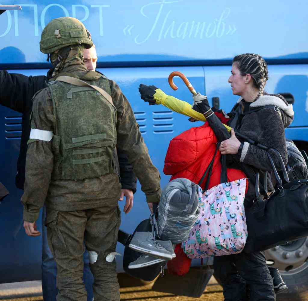 A woman evacuated from the steel mill is escorted to a bus by a pro-Russian soldier