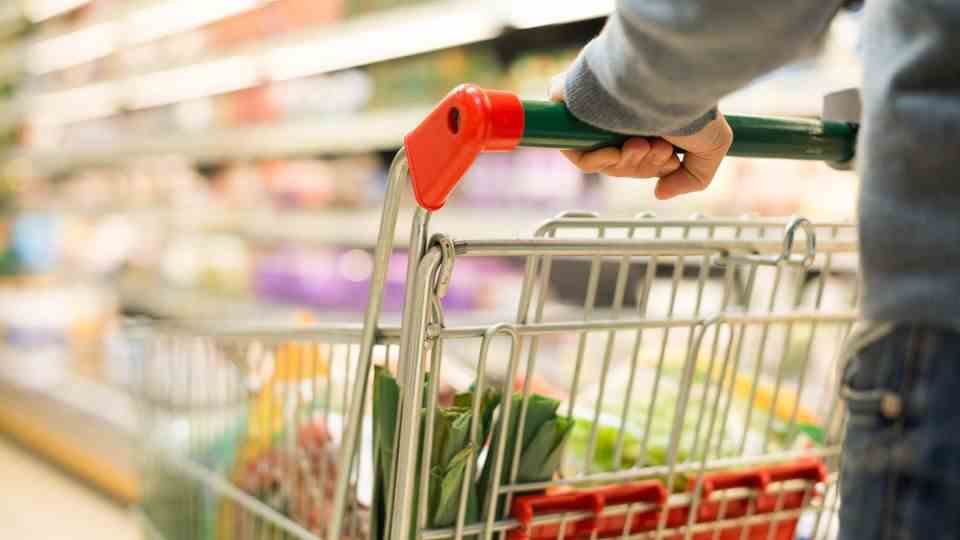 A man pushes a shopping cart through a supermarket