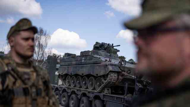Rüstungsindustrie: Zwei Bundeswehrsoldaten einer Nato-Einsatzgruppe in Litauen vor einem Schützenpanzer vom Typ Marder.