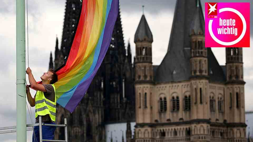 A rainbow flag in front of the Cologne Cathedral and the Church of Great St. Martin