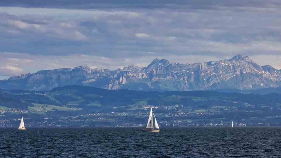 Two sailing boats are sailing in front of a mountain panorama on Lake Constance