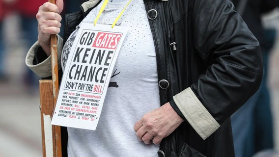A woman at a demo of the initiative "lateral thinking" has a sign that says "Don't give Gates a chance - don't pay the bill" hung around the neck.  © picture alliance Photo: Dennis Ewert