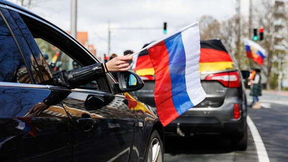 A woman holds a Russian flag out of the window of a car during a pro-Russian motorcade in Hanover, Germany.  © dpa Photo: Michael Matthey