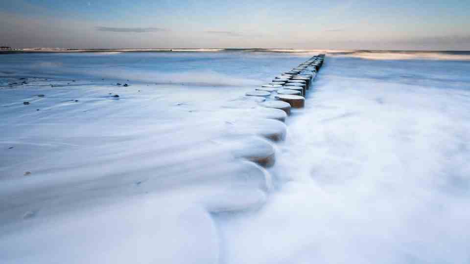 Groyne in wind and snow: Long exposure at the wintry Baltic Sea beach.