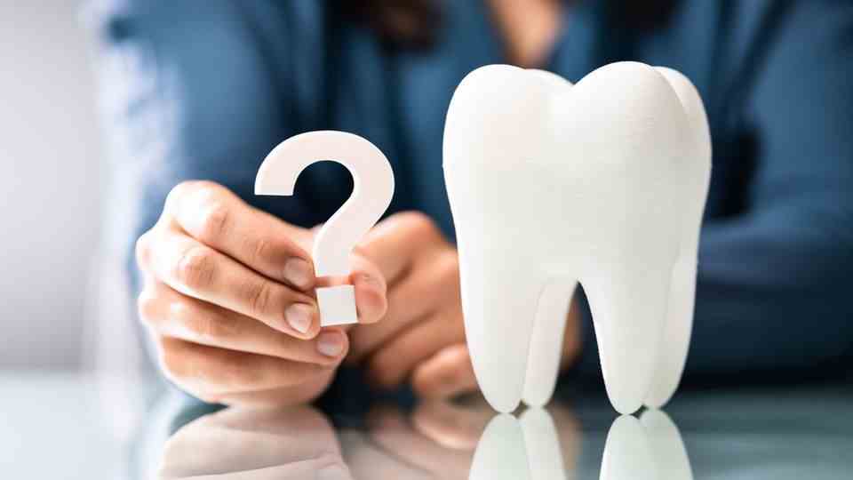 Man holding a question mark next to a tooth model