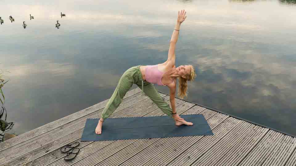 A woman does yoga in front of a lake