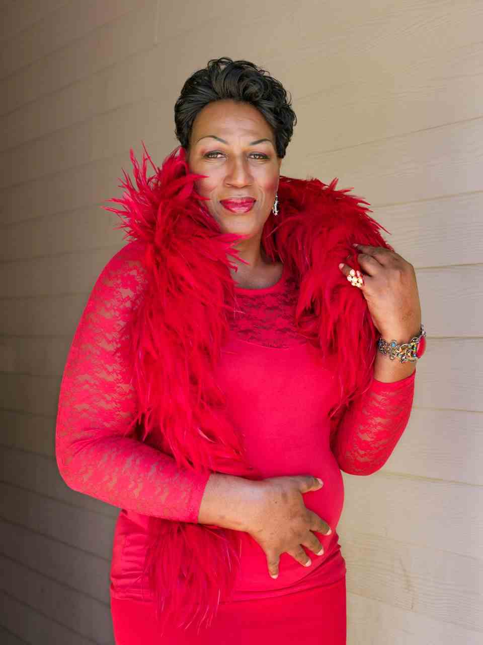 A tall African trans woman in a bright red dress and boa