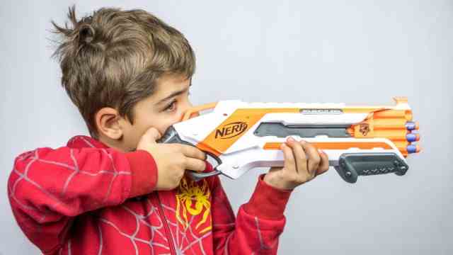 Boy with N Strike Elite toy gun from NERF Hasbro armed with foam projectiles K