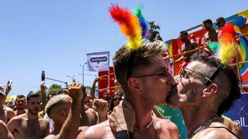 Two men kiss among participants at Tel Aviv Pride
